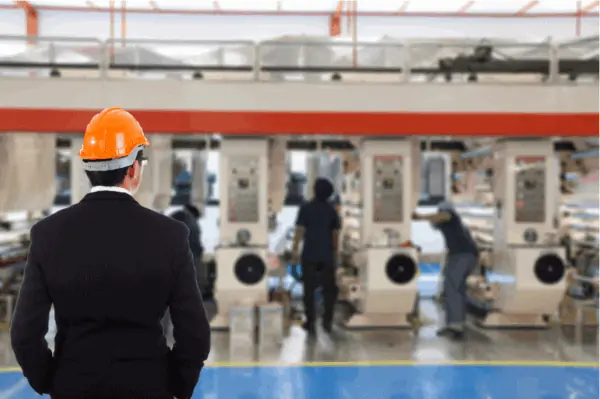Facility overseer watching employees work on machine